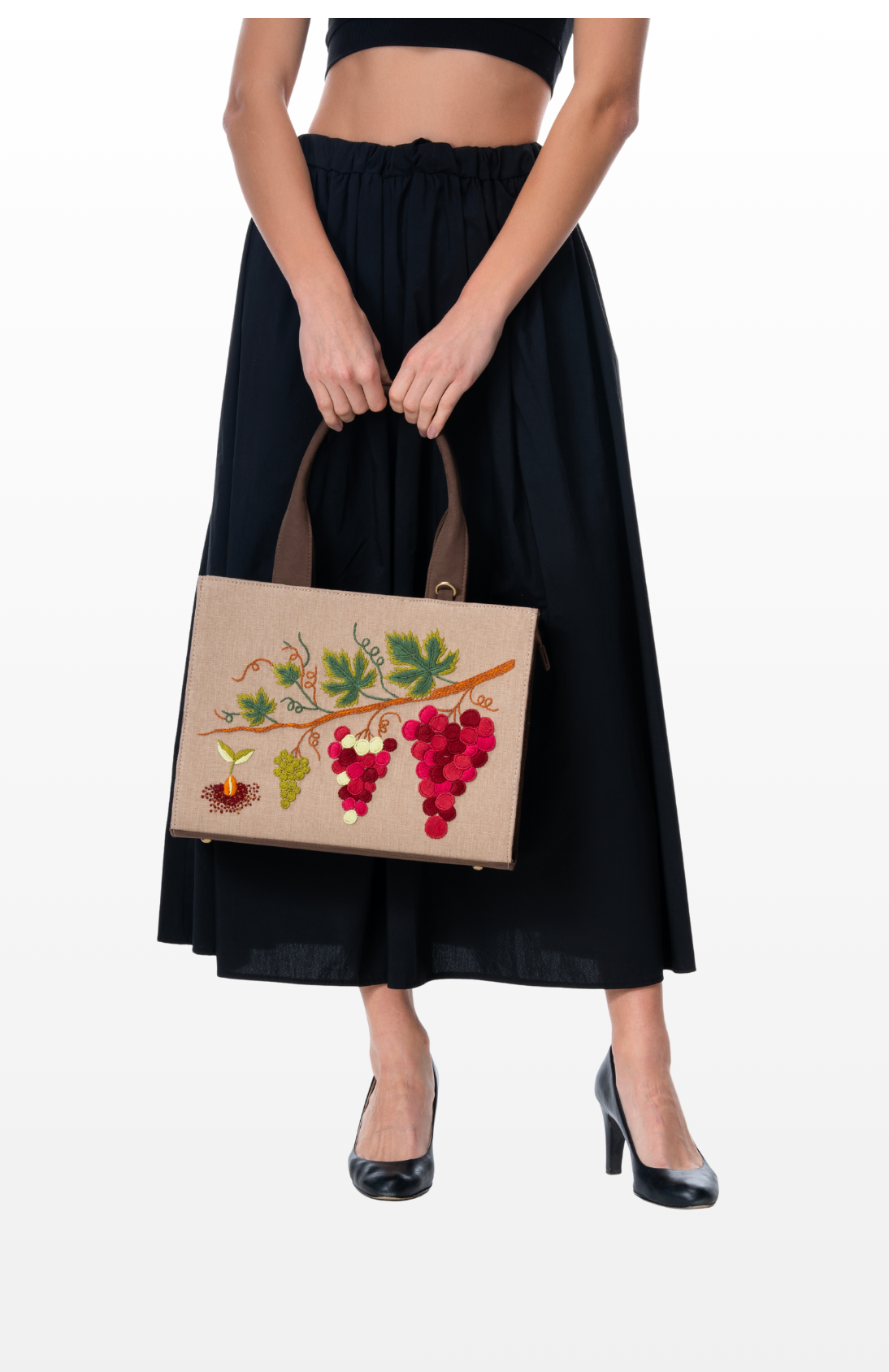 Woman holding Heirloom Vines handbag by the brand Story of Strings.