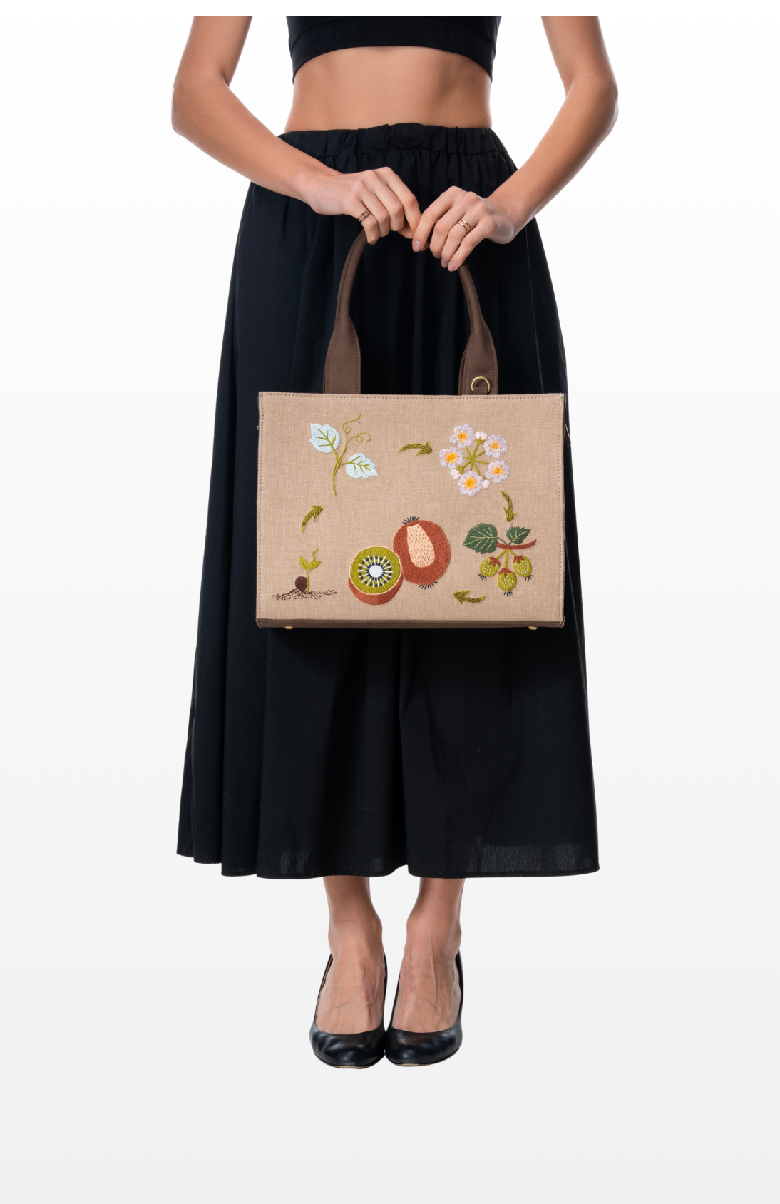 Woman holding Kiwi Orchard handbag by the brand Story of Strings.