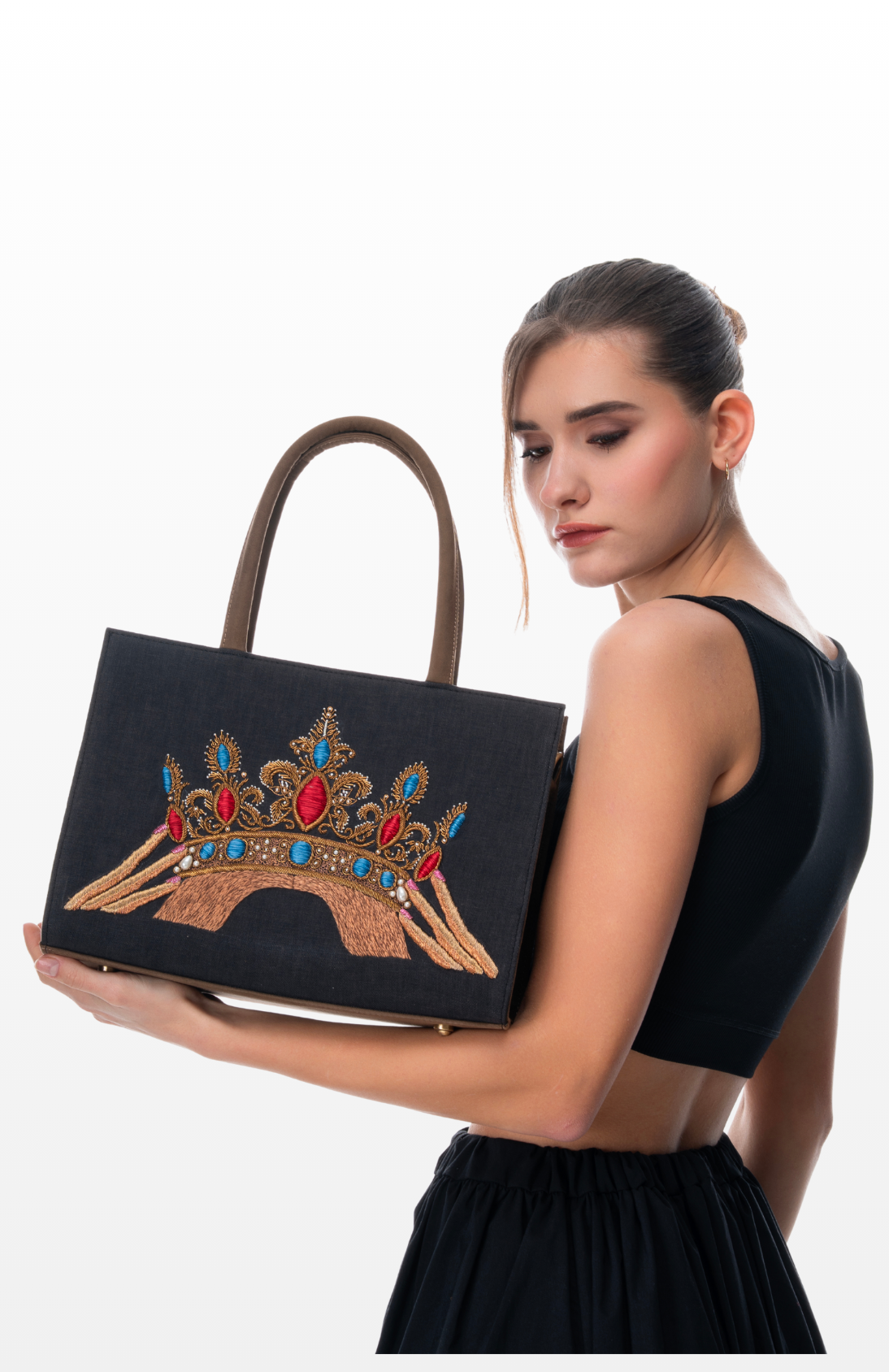 A Woman holding The Crown Jewels tote bag by the brand Story of Strings.