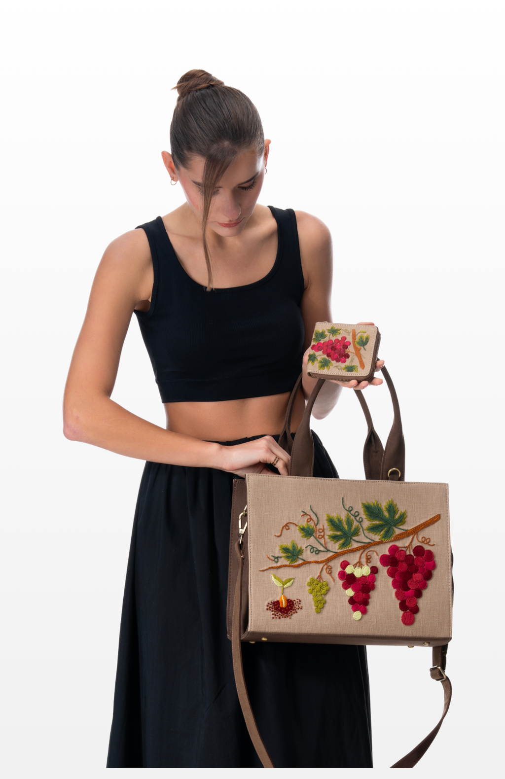 A woman holding The Noble Grape smart wallet with its handbag collection by the brand Story of Strings.