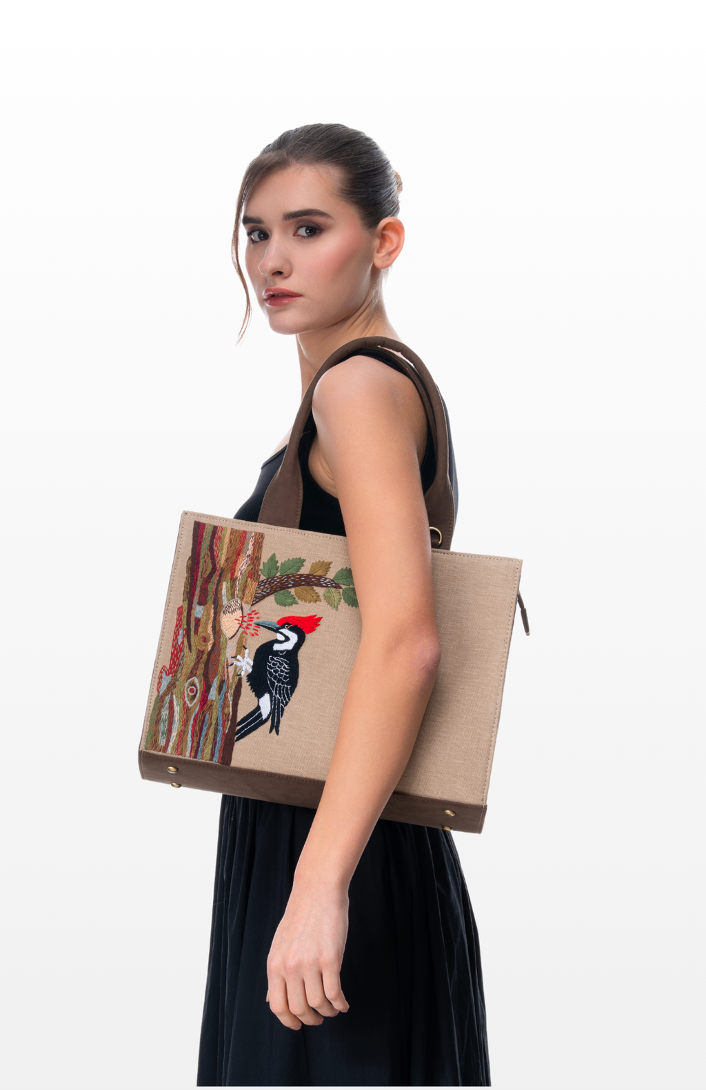 Woman wearing Woodpecker's Rhythm tote bag by the brand Story of Strings.