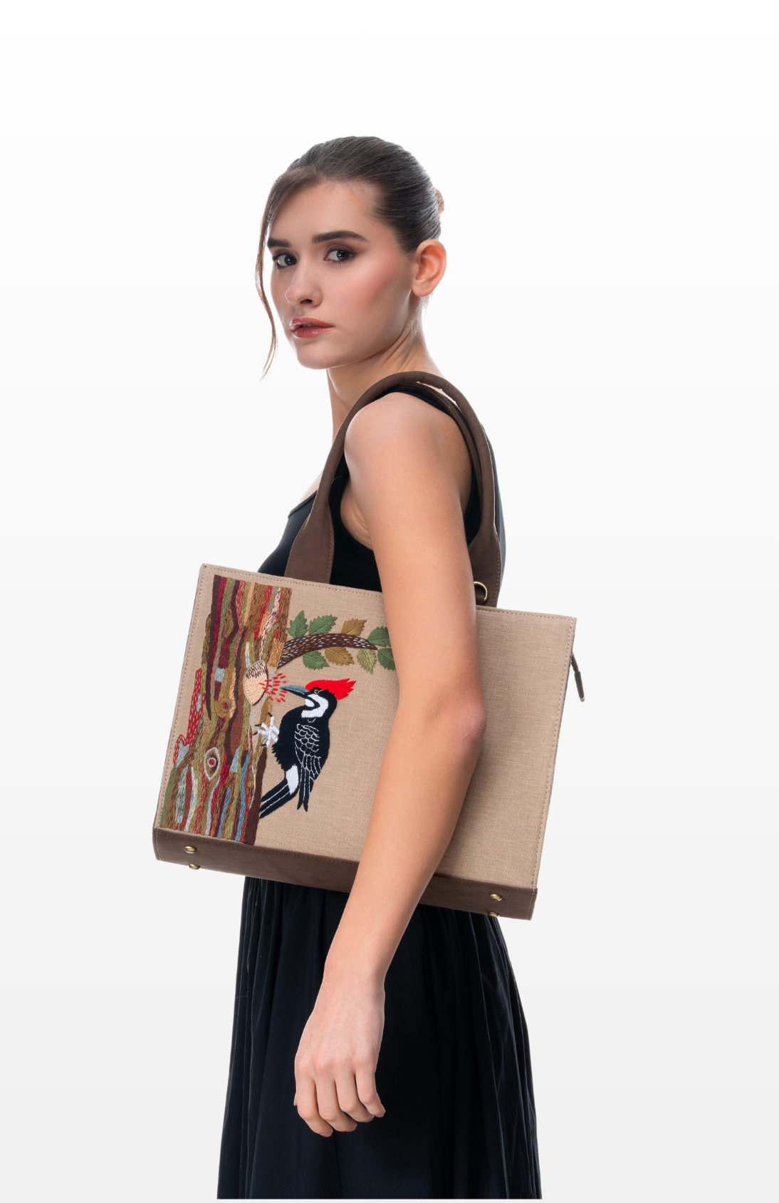 Woman wearing Woodpecker's Rhythm tote bag by the brand Story of Strings.